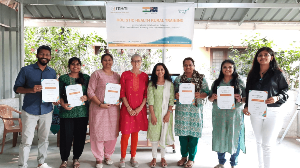 Seven Holistic Health Train the Trainer participants pose for the camera whilst holding their training certificates in India.